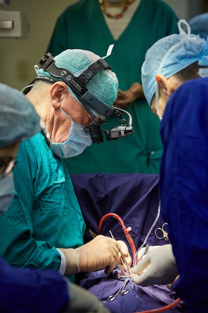 Um cirurgião com assistentes realiza uma operação em um hospital moderno. Operação de execução de equipe médica.