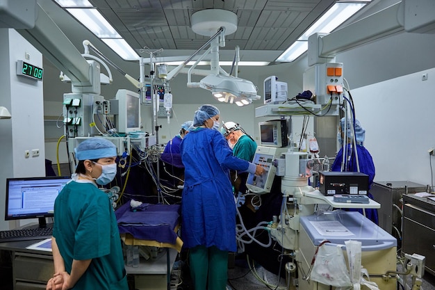 Um cirurgião com assistentes realiza uma operação em um hospital moderno. Operação de execução de equipe médica.