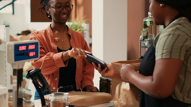 Um cliente afro-americano a pagar por mercadorias biológicas na caixa.