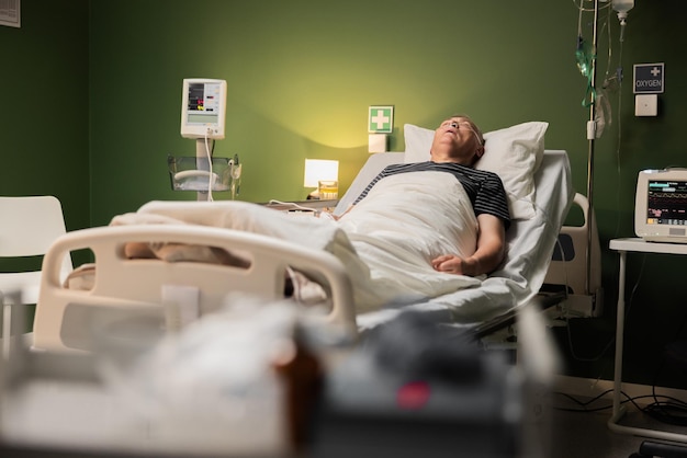 Um cliente idoso fazendo uma soneca pacífica no hospital apoiado por um tubo de respiração e um sensor de dedo