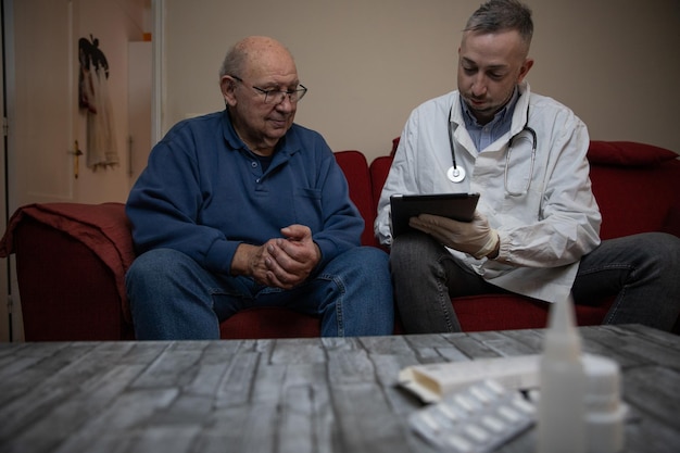 Um clínico geral e seu paciente em casa com medicamentos na mesa profissional de saúde