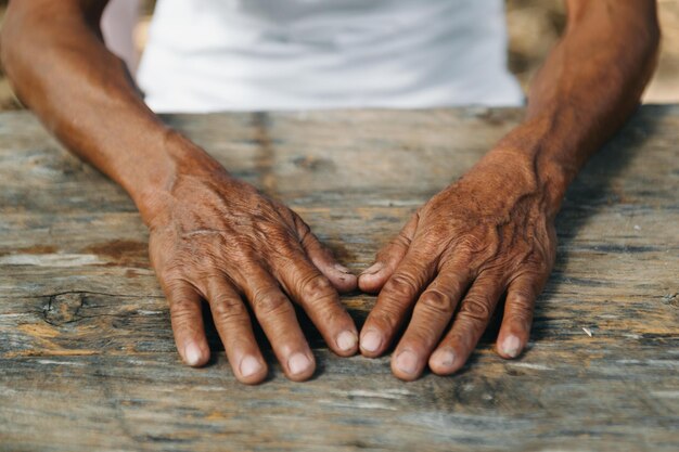 Um close de mãos enrugadas masculinas que o velho está a usar.