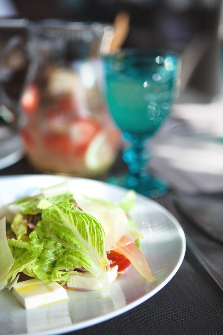 Foto um close de salada com tomates de alface e queijo num prato branco.