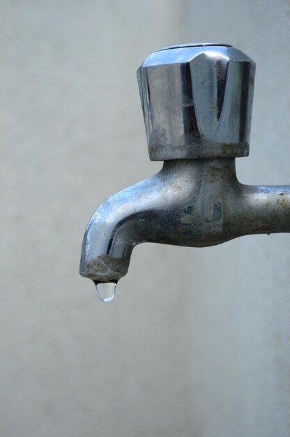 Foto um close de uma gota a gotejar da torneira.