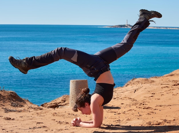 Um close de uma jovem fazendo ioga perto da praia na Espanha