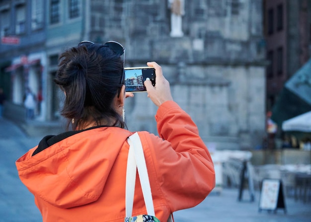 Um close de uma jovem por trás tirando fotos em seu telefone