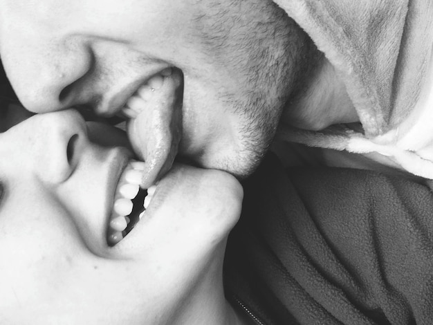 Um close de uma jovem sorridente a morder a língua do namorado.