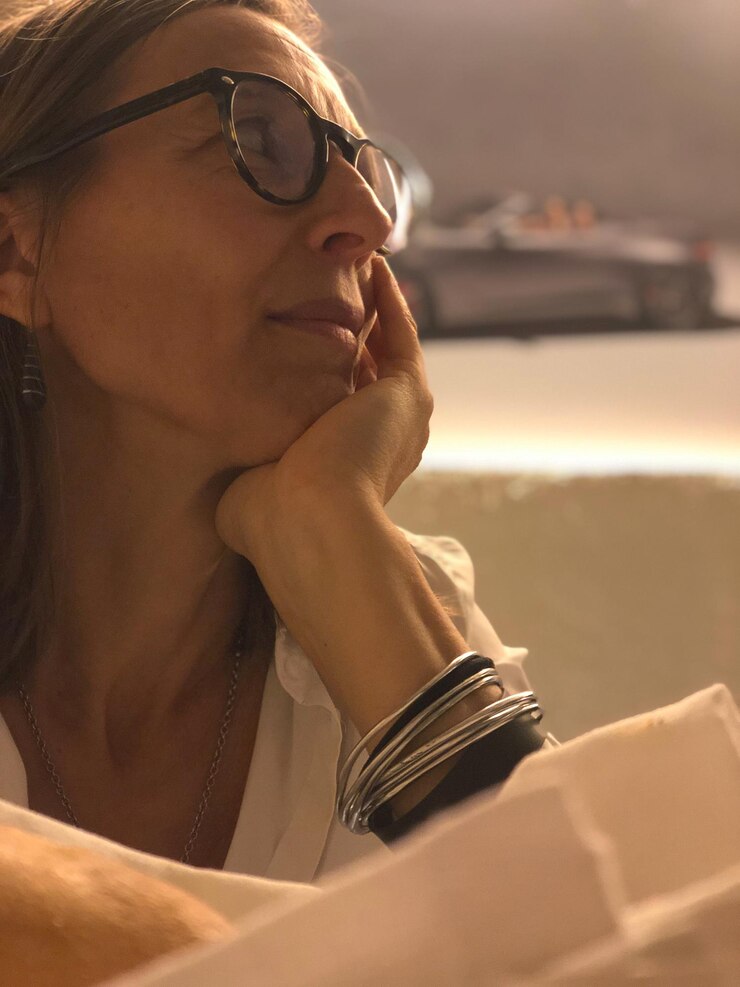 Foto um close de uma mulher madura pensativa a olhar para outro lado.