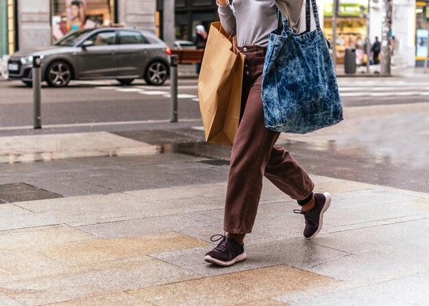 Um close de uma mulher segurando sacos de compras na rua