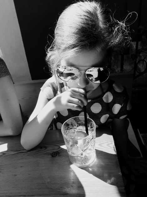 Foto um close de uma rapariga a beber na mesa.