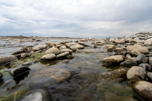 Um close-up de belas pedras molhadas grandes e pequenas em um lago em uma área rural