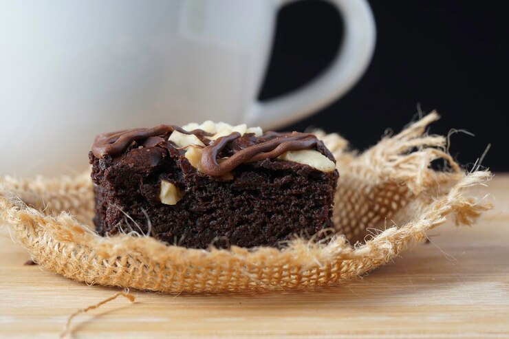 Foto um close-up de brownie de chocolate escuro úmido com porca misturada em cima em um saco castanho sobre uma mesa de madeira