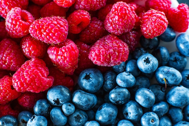 Um close-up de framboesas e mirtilo preto dividiu o quadro. Vitaminas de verão