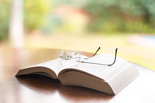 Foto um close-up de óculos sobre um livro sobre uma mesa.