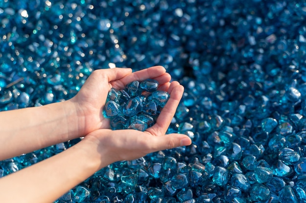 Um close up de pedras de cristal azuis na mão da mulher.