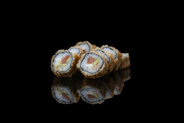 Um close up de rolinhos de sushi fritos isolados no reflexo preto