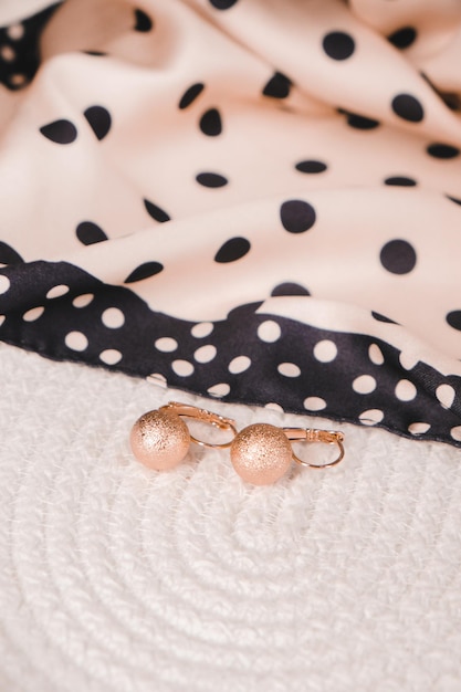 Um close-up de um brinco de bolinhas rosa e preto em uma cama.