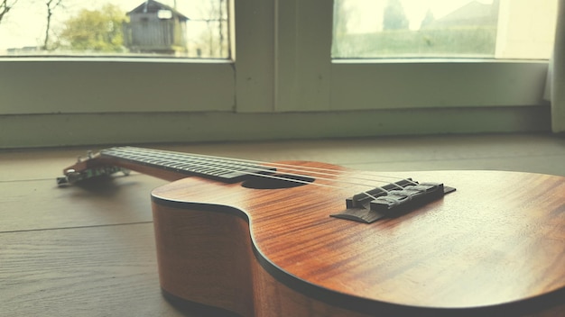 Foto um close-up de uma guitarra na mesa ao lado da janela em casa