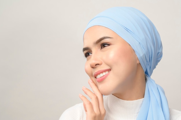 Um close-up de uma jovem e bela mulher muçulmana com um hijab isolado na parede branca