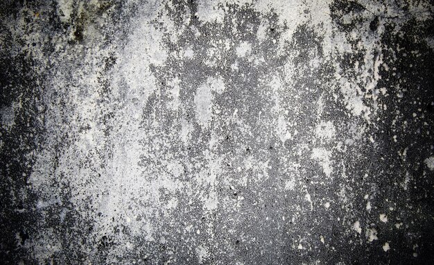 Foto um close-up de uma parede cinza com tinta branca e manchas.