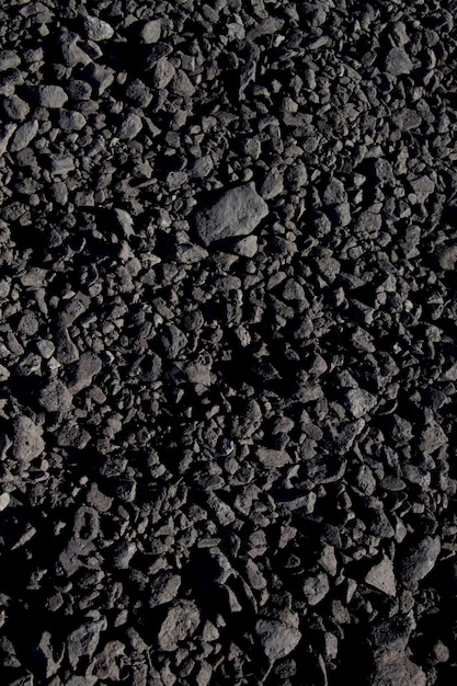 Foto um close-up de uma pilha de cascalho preto com pequenas pedras e pequenas pedras.