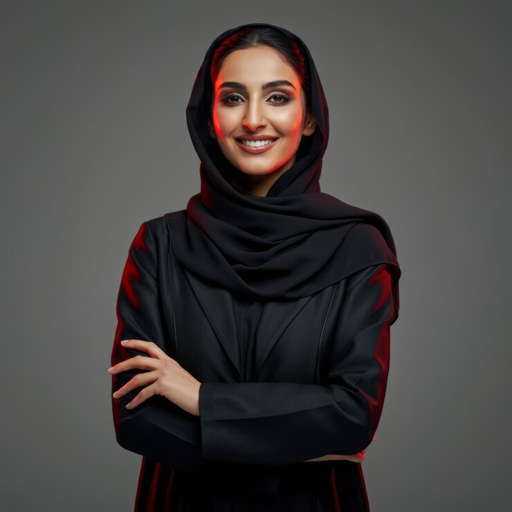 Foto um close-up de uma sorridente mulher saudita do golfo que usa o hijab com gestos de autoconfiança