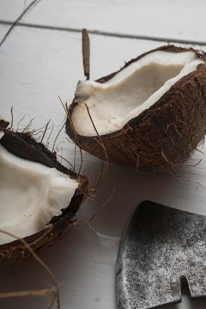 Um coco é cortado ao meio em uma mesa de madeira clara. Vista superior
