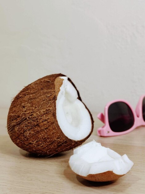 Um coco e óculos de sol sentados em uma mesa.