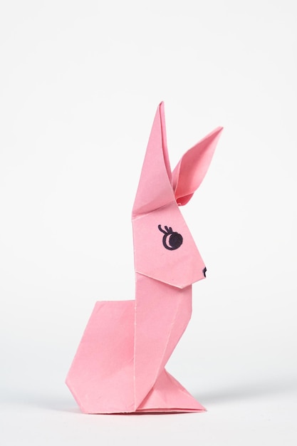 Um coelho de origami rosa em um fundo branco