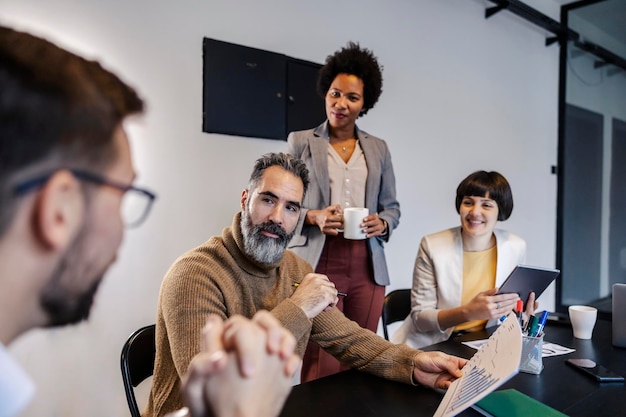 Um colega de trabalho interracial na sala de reuniões a ouvir o seu gerente com ideias.