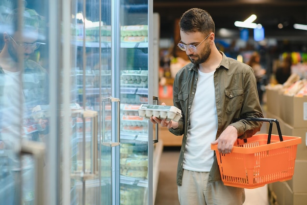 Um comprador masculino escolhe ovos de galinha num supermercado