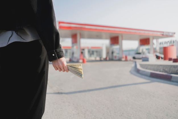 Um conceito de posto de gasolina de veículo de aumento de preço de gasolina e mão segurando dinheiro
