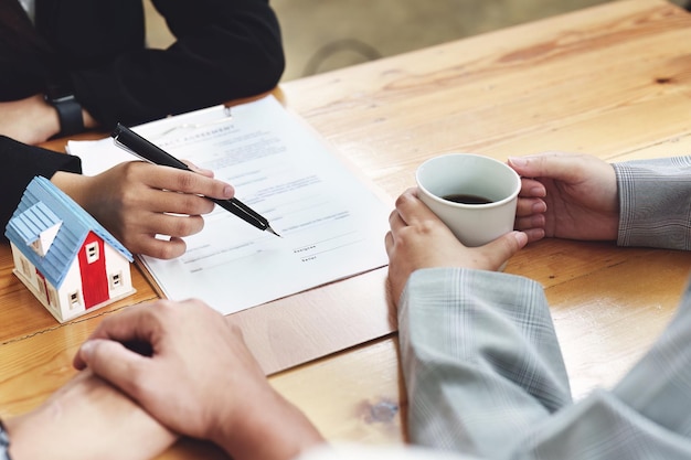 Um cônjuge que entra em um contrato de casa está lendo os termos do contrato de juros do empréstimo que o funcionário do banco ou agente imobiliário está oferecendo antes de assinar