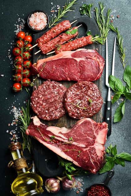 Um conjunto de bifes e carne de vitela Produtos de carne em um fundo de pedra preta Vista superior