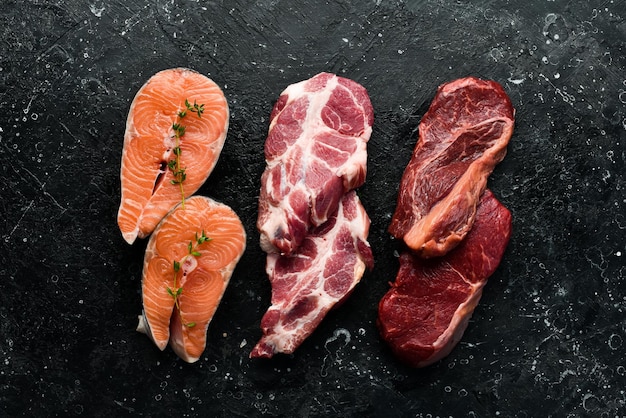 Um conjunto de carnes diferentes, carne de peixe e carne de porco Fonte de proteína animal para o corpo Em um fundo de pedra preta