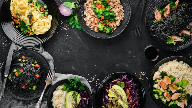 Um conjunto de comida e pratos salada de risoto de arroz de macarrão em um fundo preto espaço para texto grátis