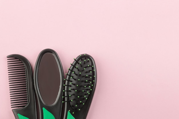 Um conjunto de diferentes escovas de cabelo e um espelho em um só estilo em um fundo rosa brilhante. vista de cima