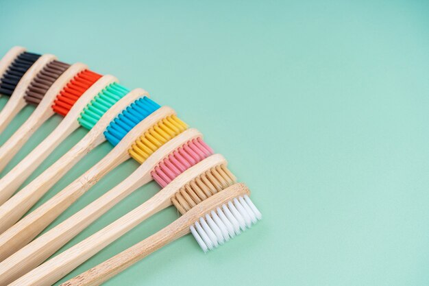 Um conjunto de escovas de dentes antibacterianas ecológicas feitas de madeira de bambu em um fundo verde claro.