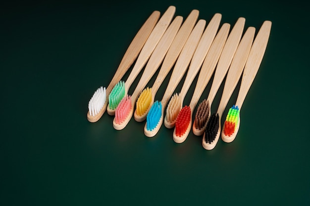 Um conjunto de escovas de dentes antibacterianas ecológicas feitas de madeira de bambu em um fundo verde escuro.