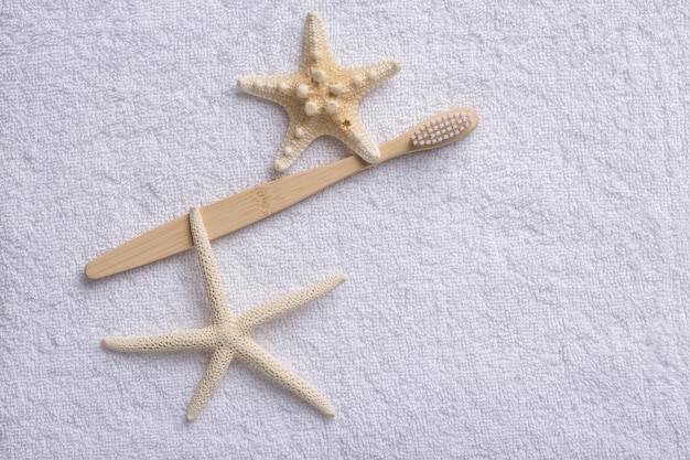 Um conjunto de escovas de dentes de madeira de bambu ecologicamente corretas com estrela do mar em uma toalha branca