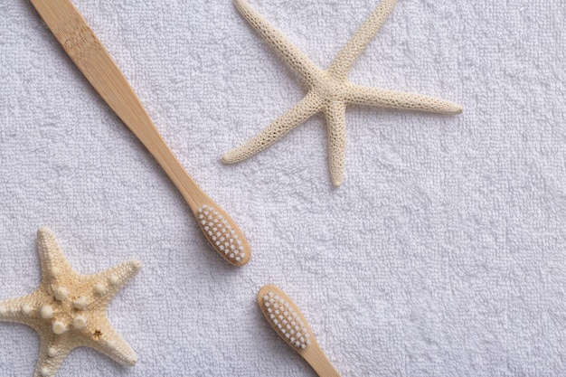 Um conjunto de escovas de dentes de madeira de bambu ecologicamente corretas com estrela do mar em uma toalha branca