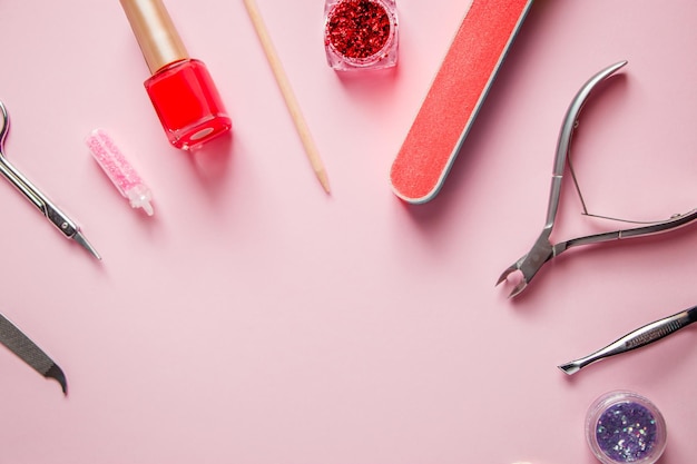 Um conjunto de ferramentas para manicure e tratamento de unhas em um fundo rosa. Local de trabalho em um salão de beleza. Lugar para texto.