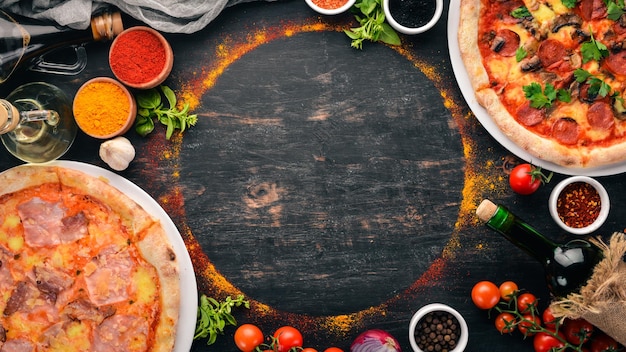 Um conjunto de pizza italiana Cozinha italiana Em um fundo preto de madeira Espaço para cópia grátis Vista superior