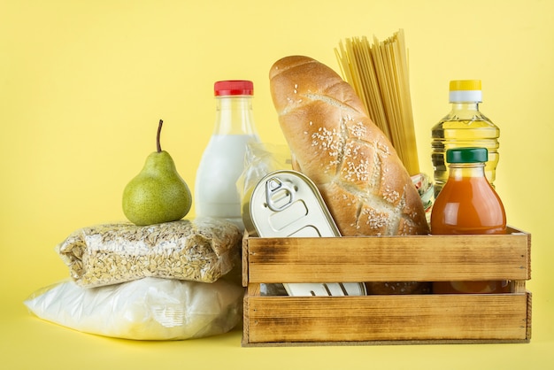 Um conjunto de produtos de armazenamento de longo prazo em uma parede amarela. doações de alimentos ou conceito de entrega de alimentos