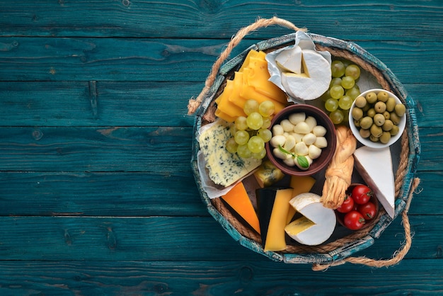 Um conjunto de queijo em uma caixa de madeira Parmesão Mamasam Mussarela Brie Feta Vista superior Em um fundo de madeira Espaço livre para o seu texto