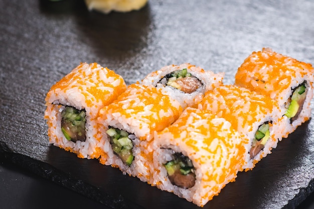 Um conjunto de rolos de sushi diferentes com caviar em fundo preto