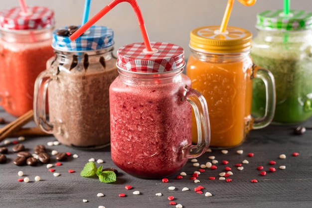 Um conjunto de smoothies coloridos diferentes em copos com fundo de madeira