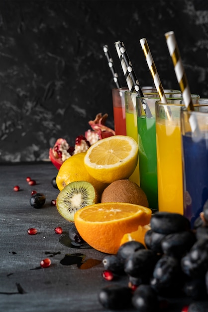 Um conjunto de sumos frescos frescos espremidos ou cocktails em um copos feitos de laranja, kiwi, limão, uvas, romãs