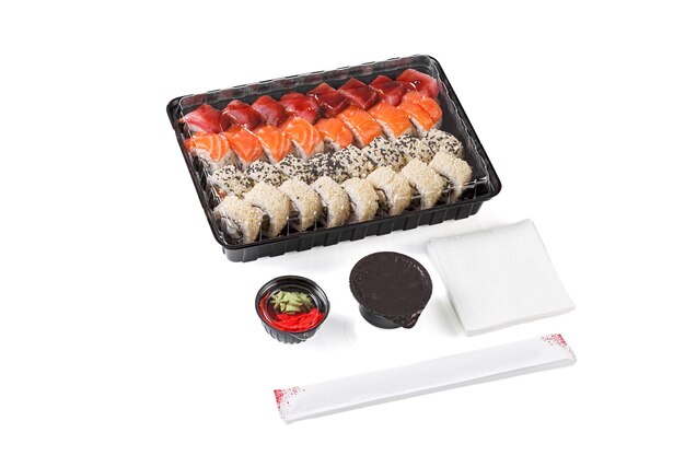 Foto um conjunto de sushi em uma caixa de entrega molho de soja pauzinhos wasabi gengibre em um fundo branco