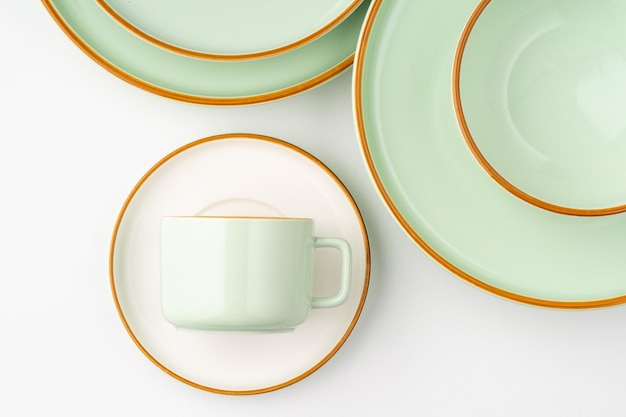 Um conjunto de talheres de cerâmica verde pastel e branco com contornos laranja
